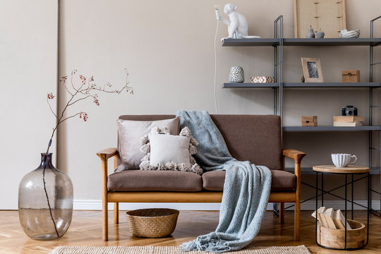 Modern interior design of living room with brown wooden sofa, gray bookstand, glassy vase with flowers, decoration and elegant accessories. Beige and japandi concept. Stylish home staging. Template. 