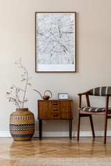 Modern composition of living room interior with brown mock up poster frame, design retro commode,  chair, etno basket with flower and elegant accessories. Template. Stylish home staging. Japandi.