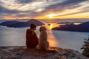 Adventurous Girl Hiking on top of a Mountain with a dog during a colorful sunset. Taken on Tunnel...