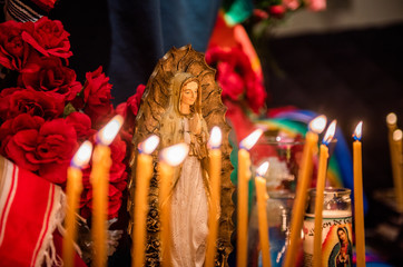 Small statue figures of the Virgin Mary and candles are lit at a church altar