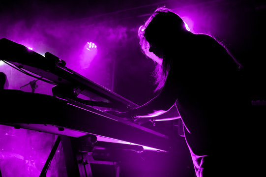 Silhouette of girl playing keyboards during concert