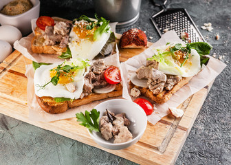 Appetizing sandwiches with pate, herbs and cheese on a wooden cutting board. Close-up