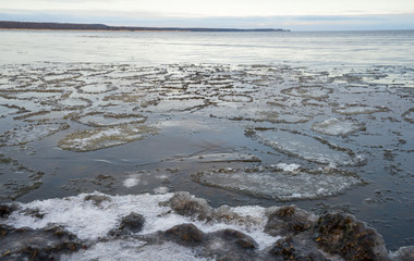 Roundish icy plates floating in coastal waters. Winter landscape in small Nordic country Estonia in late December day. smooth water, far horizon.
