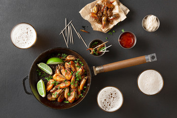 Fresh craft beer in glasses and a shrimp appetizer with herbs and sauces. Black concrete, top view