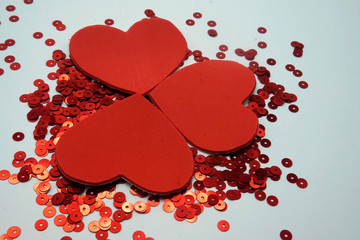 Red sequins and three red hearts on white background. Sewing and decorating accessories used for...