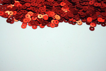 Red sequins on white background. Sewing and decorating accessories used for embellishment of dresses. Copy space.
