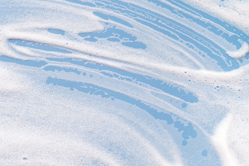 White soapy foam on a blue background. Cleaning/Washing concept..
