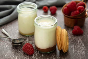 Fresh yogurt in glass jar with fruits on dark background. Healthy food, milk diary.