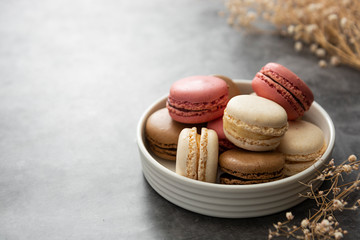 French macaron cakes in a plate close up. Cream, brown, pink, macarons with copy space.