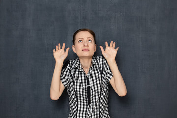 Portrait of scared young woman raising hands up and protecting herself