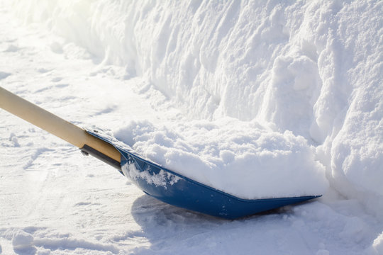 Finishing shoveling snow in the sidewalk. Snow shovel near a big snowdrift after cleaning