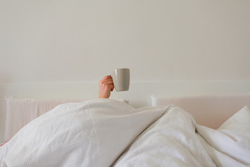 hand in bed with coffee