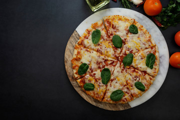 Delicious pizza on dark background, top view. Homemade round piza with cheese on dark background. Copy space.