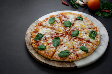 Delicious pizza on dark background, top view. Homemade round piza with cheese on dark background.