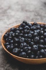 Bowl of blueberries in wooden bowl over grey background isolated. Fresh berry. Copy space.