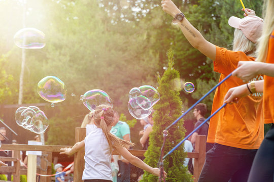 Fun with soap bubbles in an amusement park. Bubble catching children.
