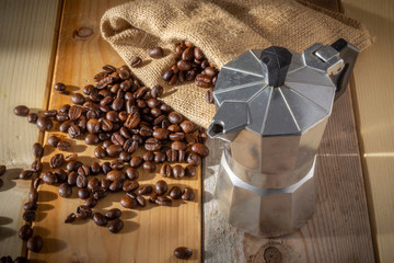 moka coffee machine, coffee beans and burlap sack on wooden background