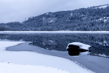 Fototapeta premium Upper Payette Lake winter cold snow and ice with dark forest