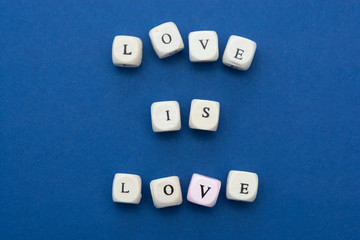 Love is love message written on wooden blocks over blue background.