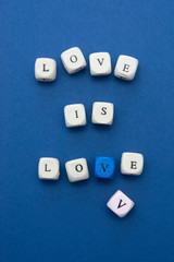 Love is love message written on wooden blocks over blue background.