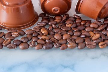 coffee beans and Italian espresso coffee brown capsules pods on a marble background