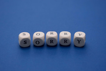 Sorry word on wooden cubes, clasic blue background, copy space. Apology message.