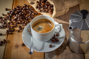 coffee in ceramic cup, moka coffee machine, coffee beans and burlap sack on wooden background