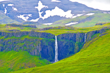 Breathtaking Grundarfoss waterfall cascade with cliff in amazing nature scenery and landscape near...