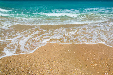 Waves on the shores of the blue sea spread to the sandy shore.