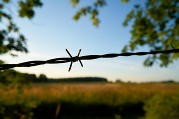 Stacheldraht an einem Zaun bei Sonnenuntergang