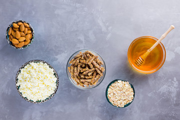 Healthy diet breakfast. Ingredients for a healthy breakfast - oatmeal, granola, honey, almonds, cottage cheese. Homemade granola on a gray background. Top view