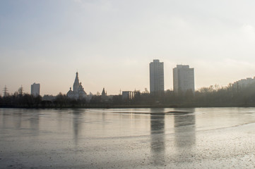 Frozen ice lake in the city in the park in winter.