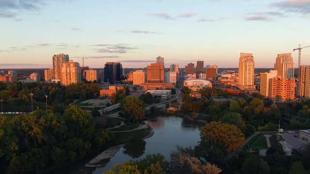 Cinematic aerial flying over Thames river with view downtown London Ontario during golden hour sunset