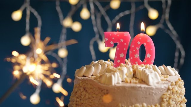 Birthday cake with 70 number pink candle and sparkler on blue backgraund. Slow motion and close-up view