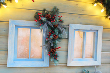 Christmas decorations in a  window on a rustic street. Fir branches and pine cones in winter, New Year celebration, magic of the holiday