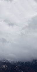 Fototapeta premium dramatic Alps mountains foggy environment gray clouds background moody nature landscape vertical wallpaper photography with empty copy space for your text