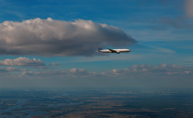 Naklejka na ściany i meble The passenger airplane cruising above the clouds