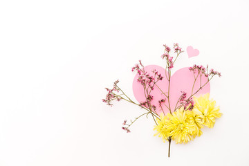 A large pink hear decorated with small pink flowers and yellow chrysanthemums on a white background