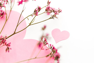 A large pink heart with a place for text decorated with small pink flowers on a white background