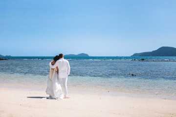 Fototapeta na wymiar Couple on their wedding day on an island in Asia by the sea