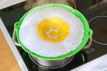 Pan on the stove with silicone lid which keep the liquid and foam in the pan. The foam comes out through the holes under the chamomile in the center of the lid, accumulates in the recess. View top