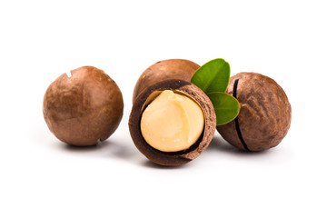 Macadamia nut with pieces and green leaves isolated on a white background