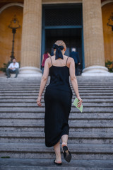 Fototapeta na wymiar young girl in black dress walks on European streets
