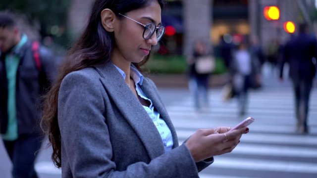 South Asian woman in spectacles holding mobile phone and writing text while checking mail box on website, millennial employee browsing web pages for communicate via cell app