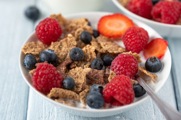 Healthy breakfast of granola chips with blueberries, raspberries and strawberries on white desk.