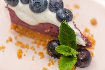 Close up on the baked vanilla and berries flavour cheesecake swirled with blueberry sauce on a digestive biscuit crumb