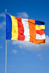 Waving colorful Buddhist Flag in cloudy blue sky background 