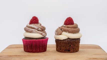 chocolate cupcake with frosting and raspberry garnish on wodden board