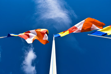 Waving colorful Buddhist Flags in cloudy blue sky background 