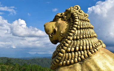 Brave Lion Posture sitting Golden Statue on a mountain view top cliff 